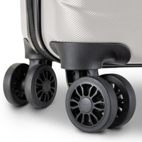 Close-up of a hard-shell suitcase corner showing a textured light gray exterior, black zipper track, and four black spinner wheels on a clean white background.