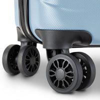 Close-up of a light blue hardshell suitcase showing the lower corner, zipper track, and four spinner wheels in black.