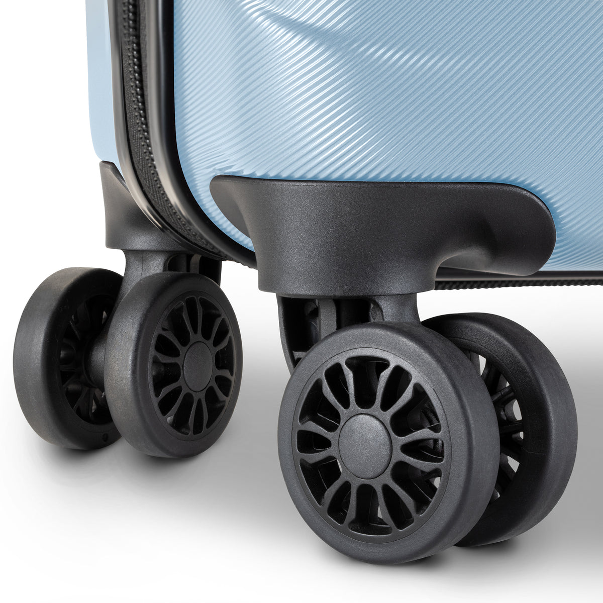 Close-up of a light blue hardshell suitcase showing the lower corner, zipper track, and four spinner wheels in black.
