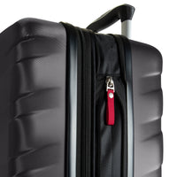 Close-up of a black hard-shell suitcase with a textured exterior, a telescoping handle, and a red luggage tag on a black zipper pocket, set against a plain white background.