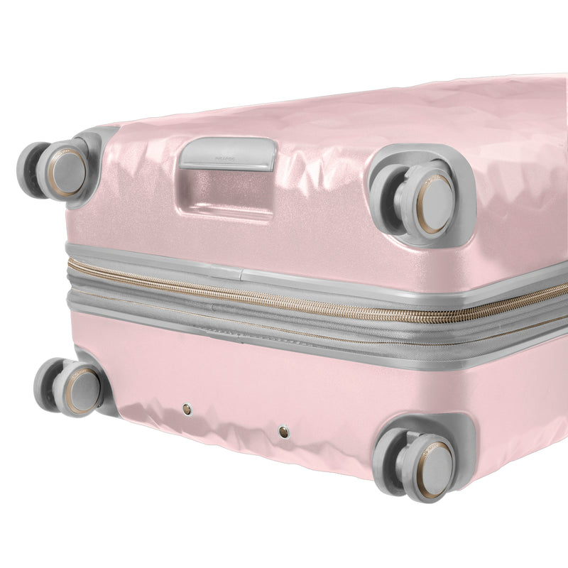 close up of  wheels on blush rolling check in luggage
